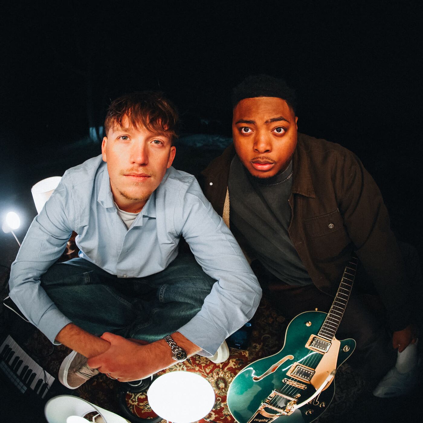 Jude and Sincer with a guitar on a rug by the lake at night
